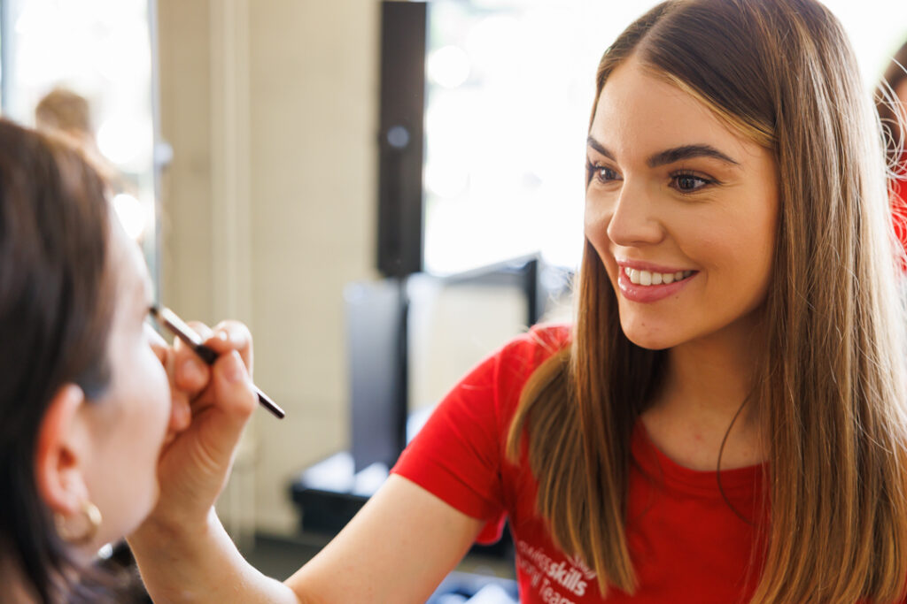 Make-up Training mit Teilnehmerin beim Schminken eines Modells im Coaching