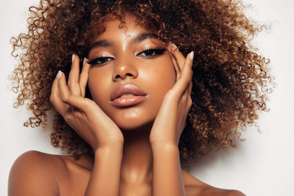 Frau mit dunkler Haut, Sommersprossen und natürlichem Glow Make-up