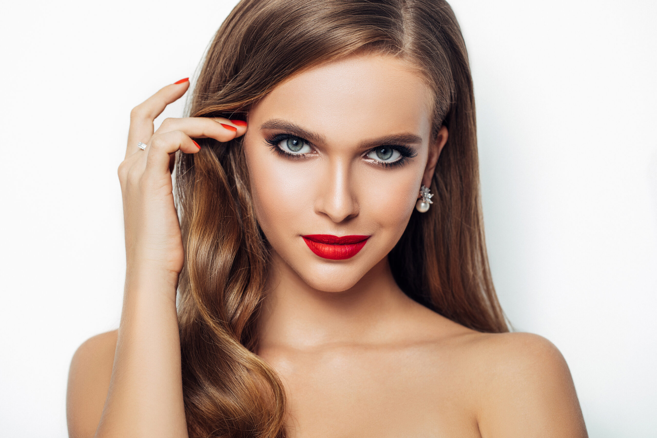 Frau mit rotem Lippenstift, ebenmässigem Teint und elegantem Augen-Make-up, frontal aufgenommen