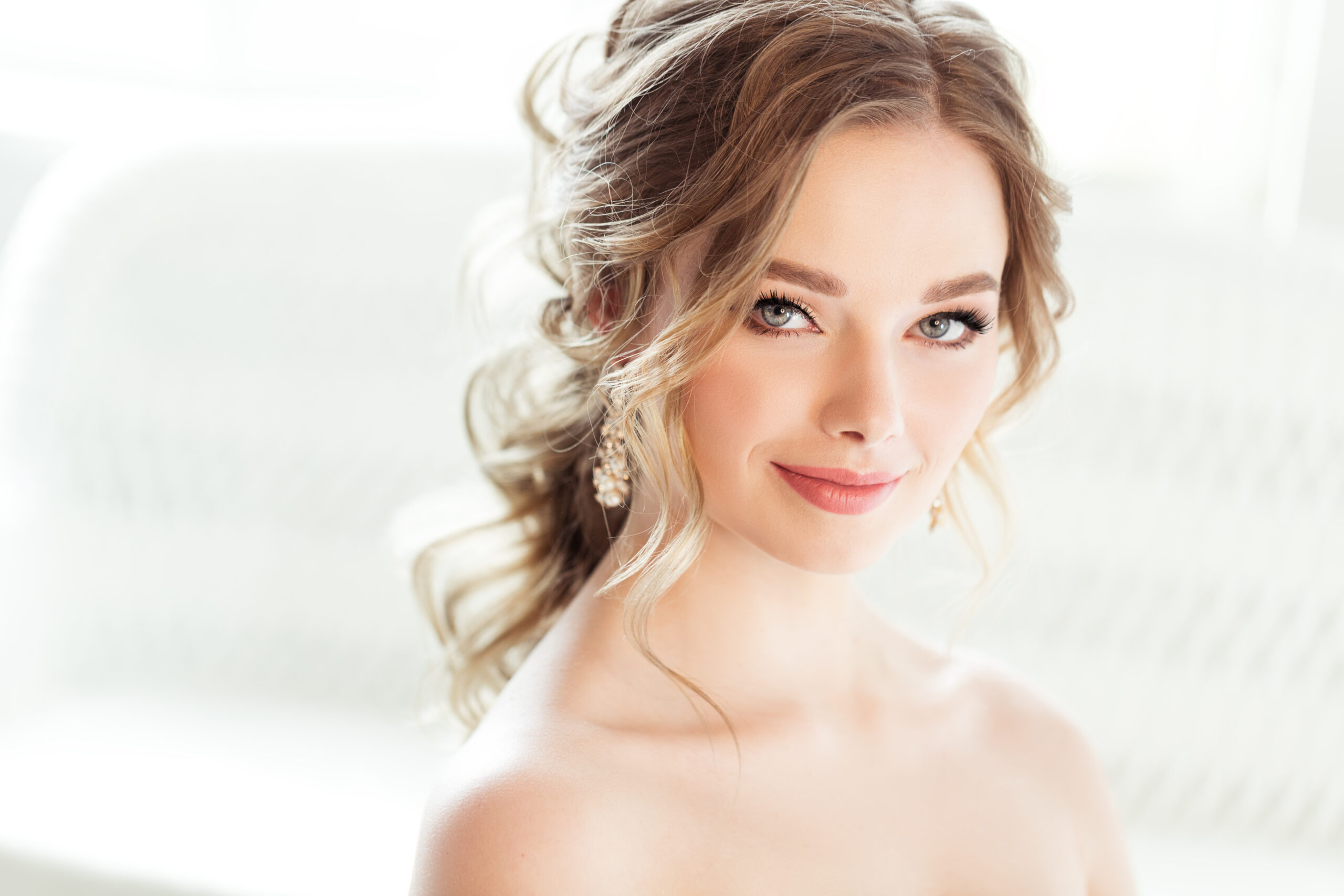 Braut mit halboffener, lockiger Frisur und natürlichem Nude Make-up Look