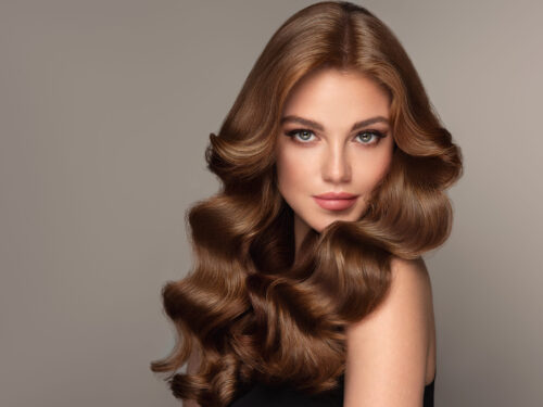 Frau mit glänzendem, braunem Haar in Hollywood Waves und glamourösem Look