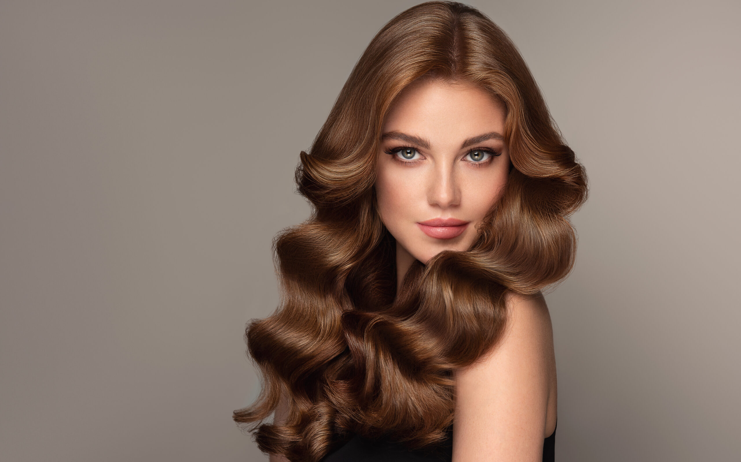 Frau mit glänzendem, braunem Haar in Hollywood Waves und glamourösem Look