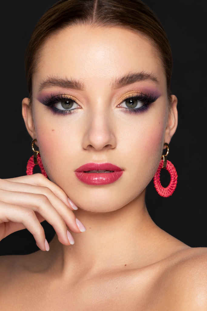 Beauty Portrait mit gold-violetten Smokey Eyes, Glow Skin und pinken Statement-Ohrringen